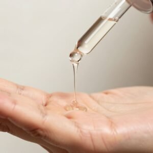 A-close-up-of-a-glass-dropper-dispensing-a-clear-concentrated-drop-of-the-Niacinamide-Arbutin-serum-onto-clean-fingertips-for-precise-application